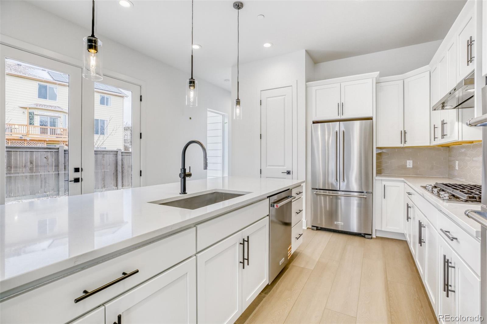 672 Apex Street Erie, CO 80516 - Photo 4 of 19 a kitchen with white cabinets and stainless steel appliances