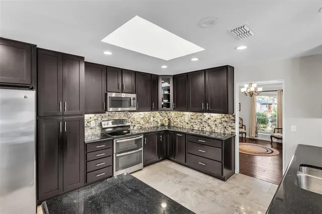 a kitchen with stainless steel appliances granite countertop wooden cabinets a stove a sink and a refrigerator