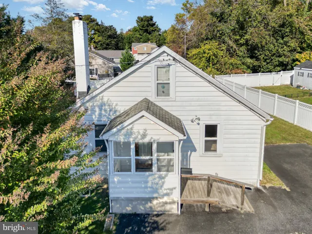 a view of a white house next to a yard with wooden fence