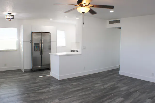 an empty room with wooden floor and a ceiling fan