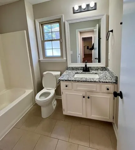 a bathroom with a granite countertop sink toilet and mirror
