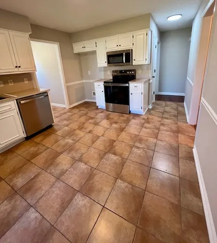 a kitchen with stainless steel appliances a sink a stove a microwave a counter top space and cabinets