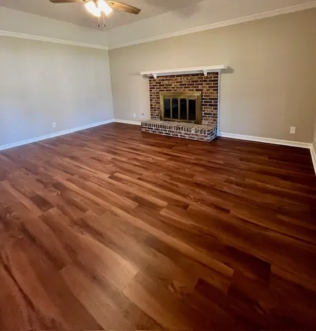 a view of an empty room with wooden floor fireplace and a window