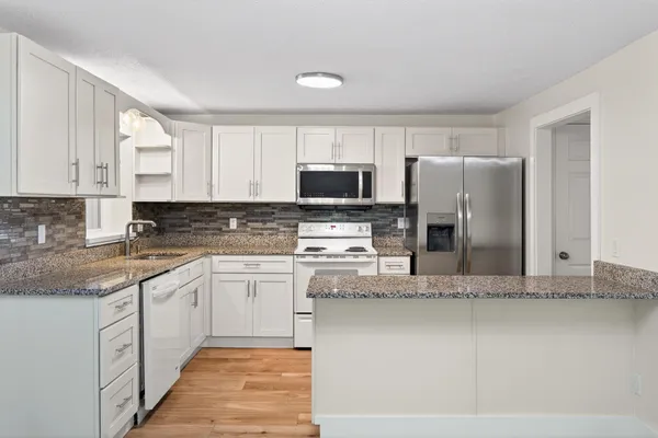 a kitchen with stainless steel appliances granite countertop a stove a sink and a refrigerator