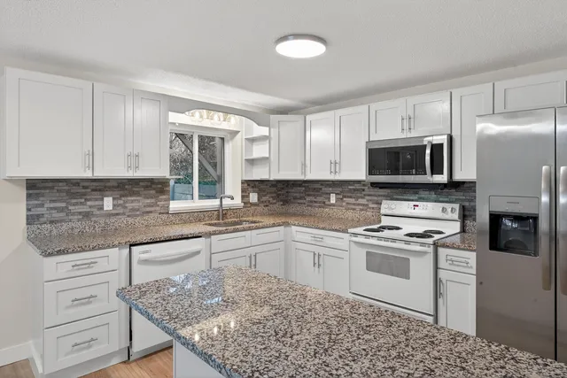 a kitchen with kitchen island granite countertop a stove sink and microwave