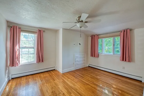 a view of empty room with wooden floor and fan