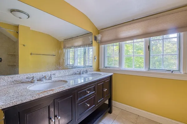 a bathroom with a granite countertop sink and a large mirror next to a window