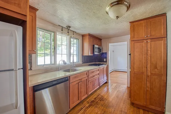 a kitchen with stainless steel appliances granite countertop a refrigerator a sink dishwasher and wooden cabinets with wooden floor
