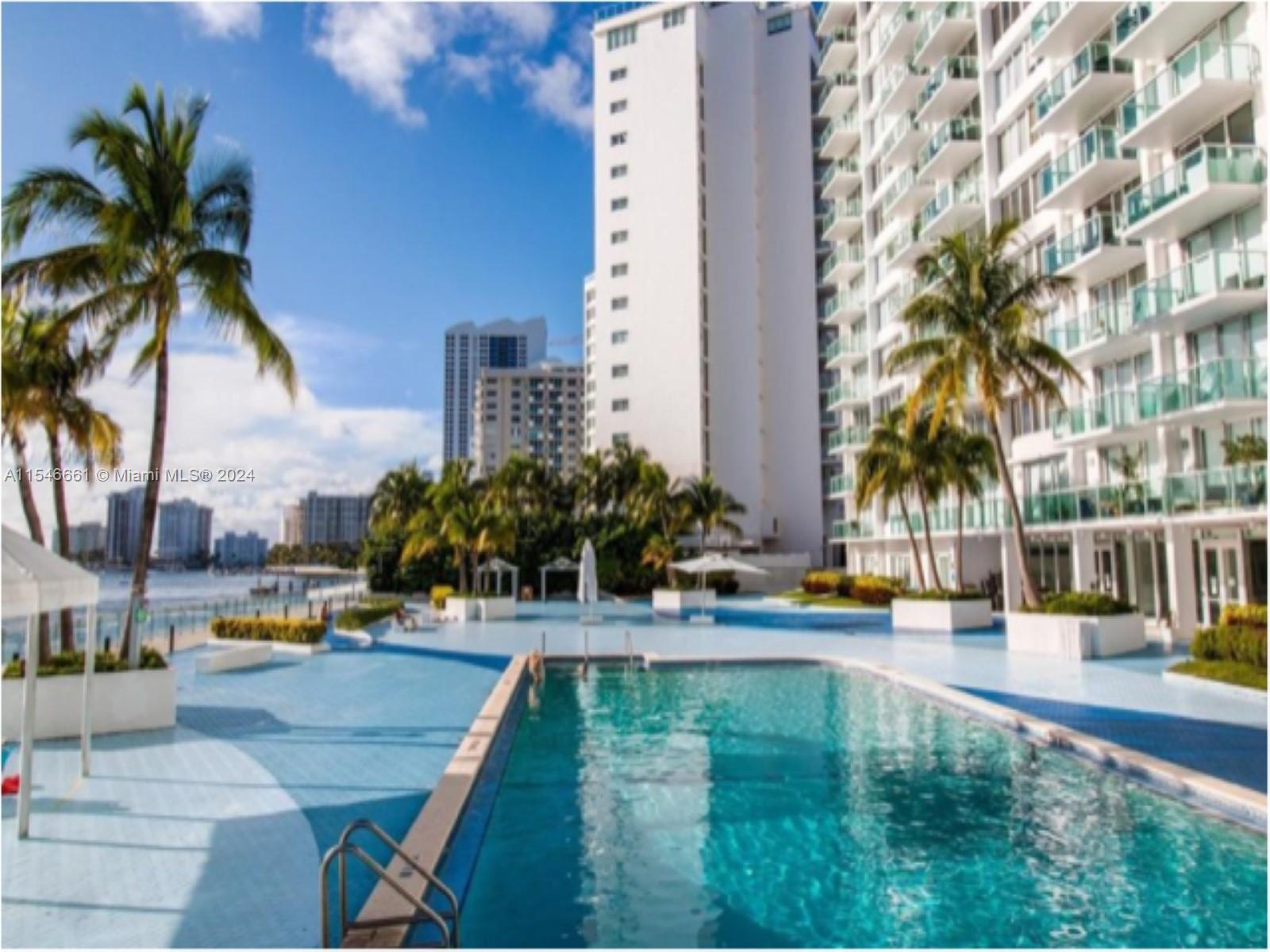 1035 West Avenue, Unit 802 Miami Beach, FL 33139 - Photo 12 of 14 a view of a swimming pool with a lawn chairs and palm tree