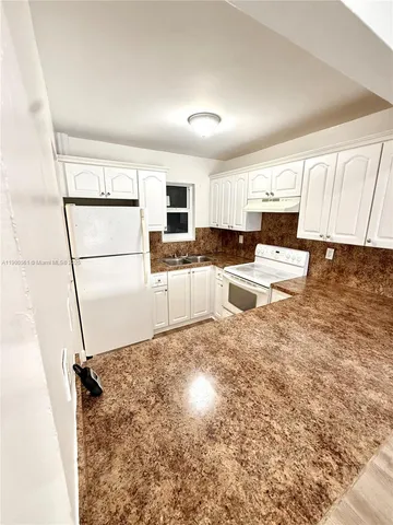 a kitchen with kitchen island a sink a stove a refrigerator and white cabinets