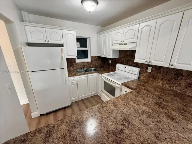 a white kitchen with sink and cabinets
