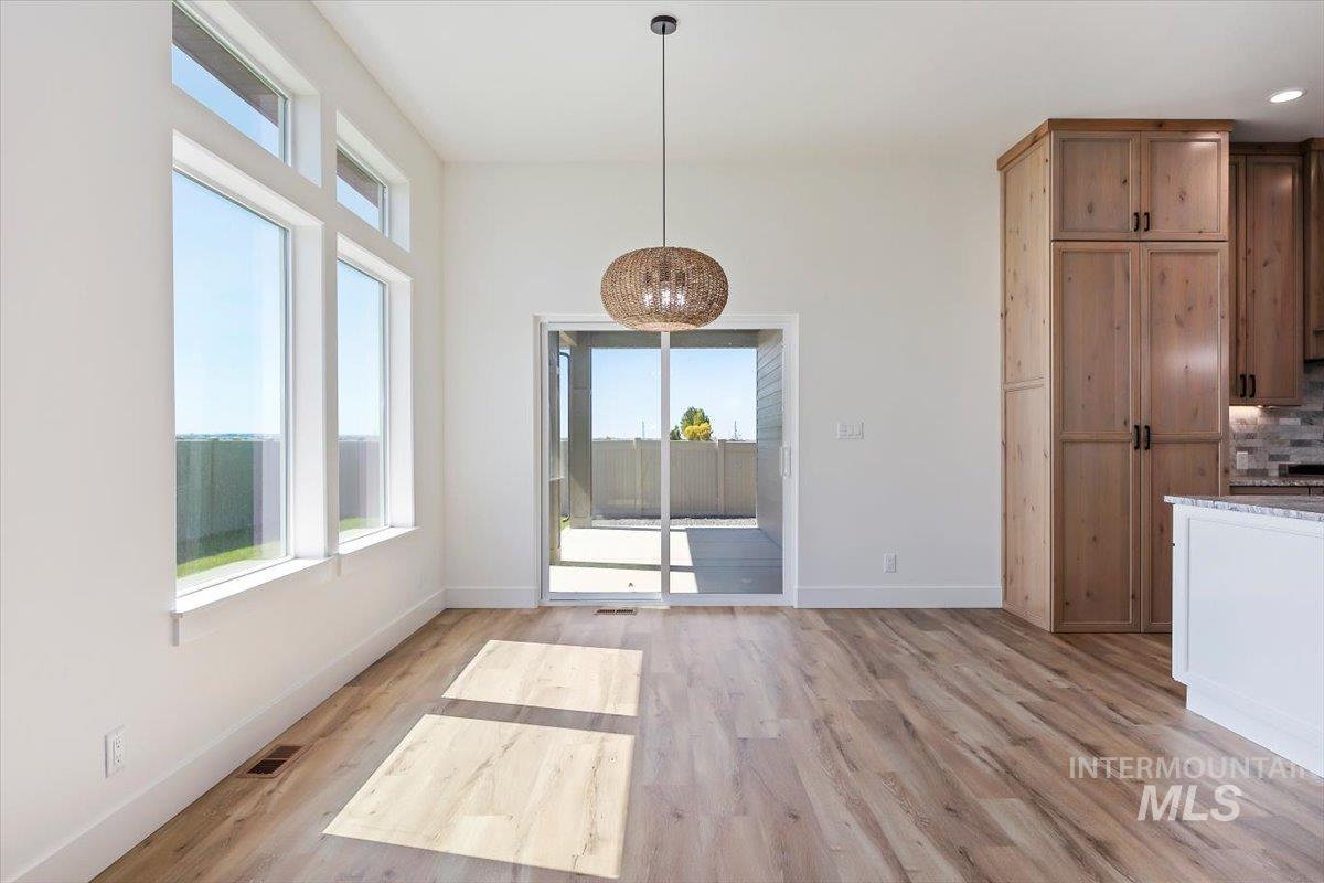 563 Moonstone Road Kimberly, ID 83341 - Photo 11 of 48 Light wood-finish flooring, ample natural light from multiple windows, sliding glass door access to an outdoor area, wooden cabinetry, and a contemporary pendant light fixture