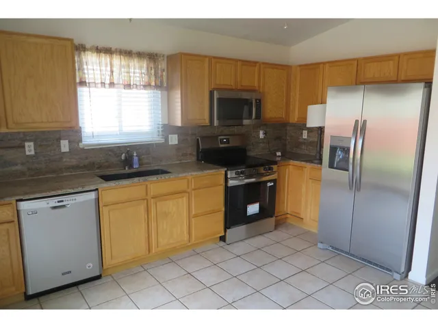 a kitchen with stainless steel appliances a sink a stove a microwave a refrigerator a counter space and cabinets