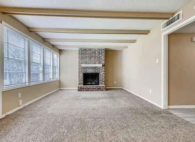 a view of an empty room with a fireplace and a window