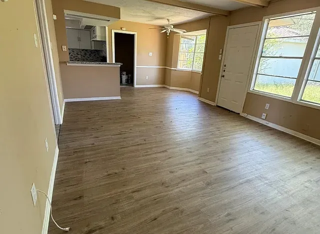 a view of a big room with wooden floor and windows