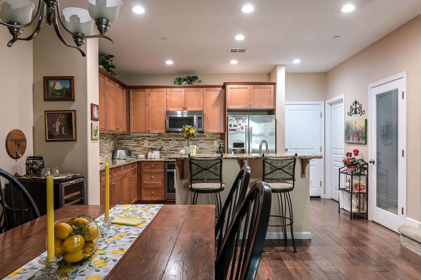 124 Larkspur Loop Morgan Hill, CA 95037 - Photo 10 of 26 a kitchen with stainless steel appliances granite countertop a stove top oven a refrigerator a sink dishwasher a dining table and chairs with wooden floor