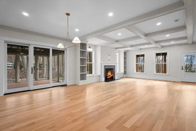 an empty room with wooden floor fireplace and windows