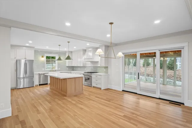 a large kitchen with a large counter top a sink stainless steel appliances and cabinets