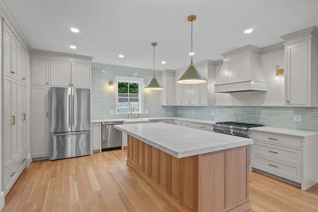 a kitchen with stainless steel appliances granite countertop a sink a stove a refrigerator and island with wooden floor