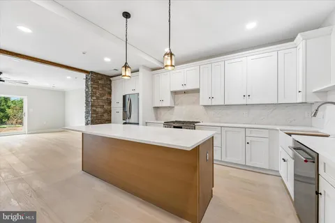 a kitchen with stainless steel appliances granite countertop a sink a stove a refrigerator and white cabinets