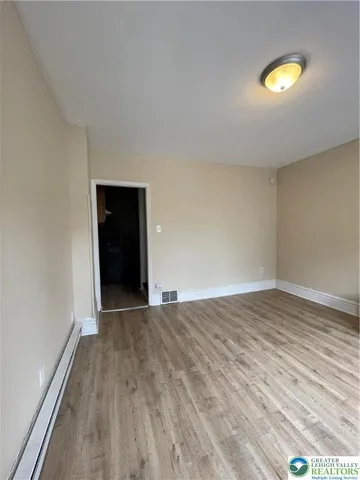 a view of empty room with wooden floor and fan