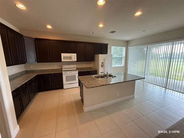 a large kitchen with kitchen island granite countertop a sink and a stove top oven