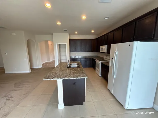 a kitchen with stainless steel appliances granite countertop a refrigerator a sink a stove a microwave and island