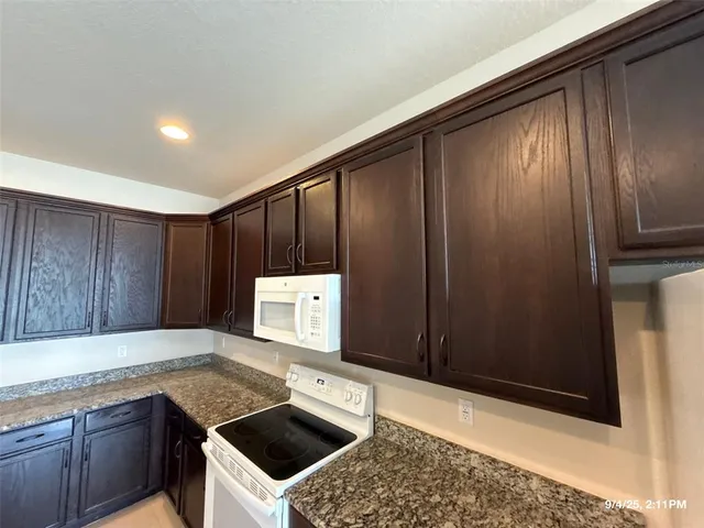 a kitchen with granite countertop wooden cabinets and white appliances
