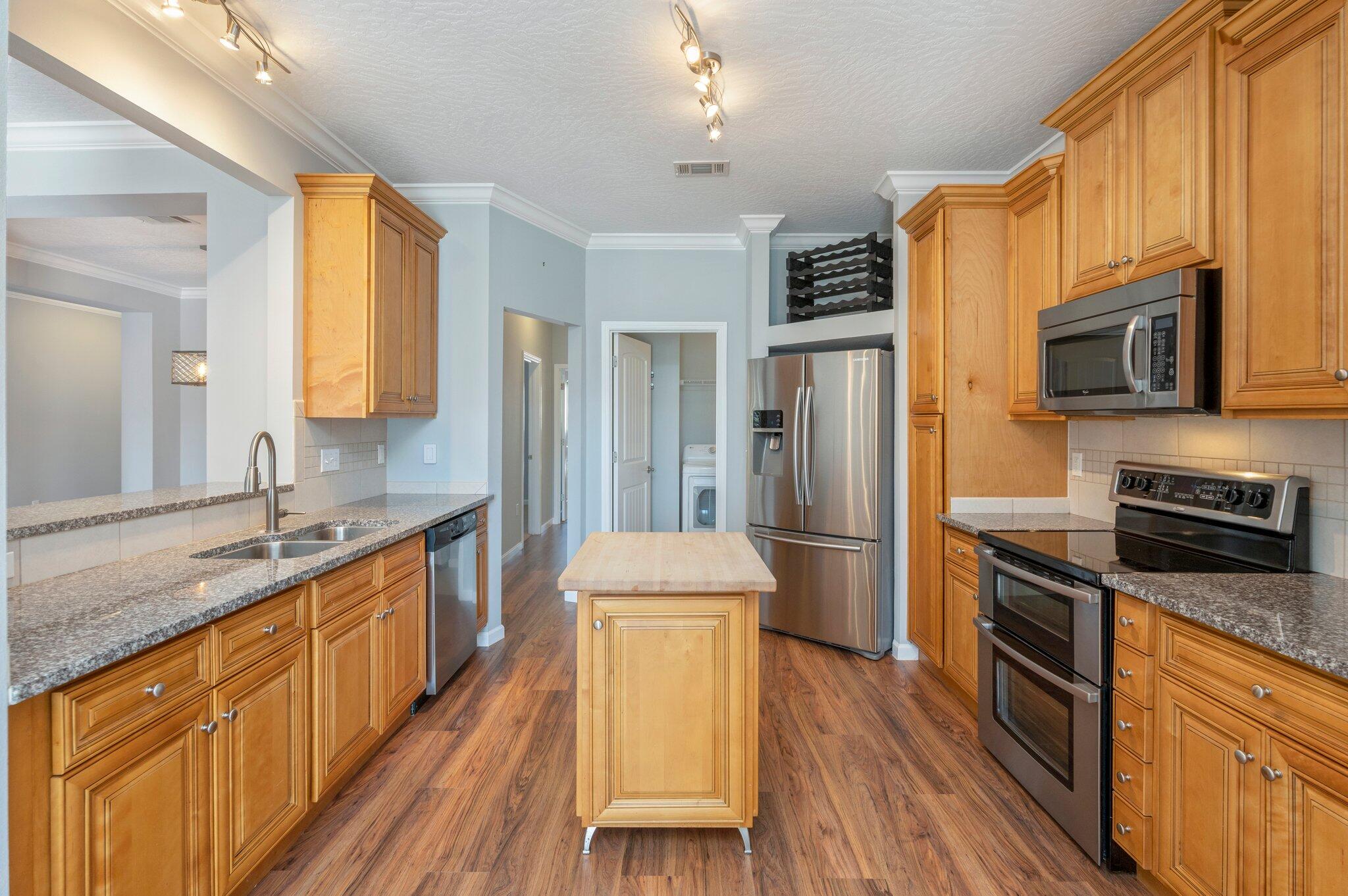 4623 Hermosa Road Crestview, FL 32539 - Photo 11 of 41 a kitchen with stainless steel appliances granite countertop a refrigerator a stove top oven a sink dishwasher and wooden cabinets with wooden floor