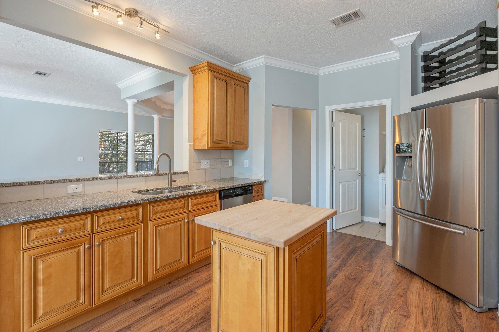 4623 Hermosa Road Crestview, FL 32539 - Photo 13 of 41 a kitchen with stainless steel appliances granite countertop a refrigerator a sink dishwasher and wooden cabinets with wooden floor