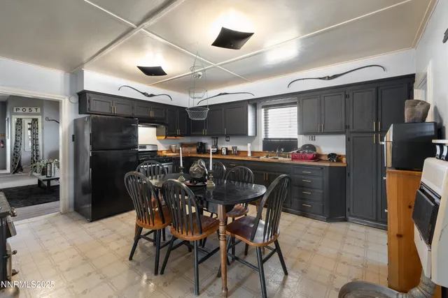 a kitchen with stainless steel appliances kitchen island granite countertop a refrigerator a stove a sink a dining table and chairs with wooden floor