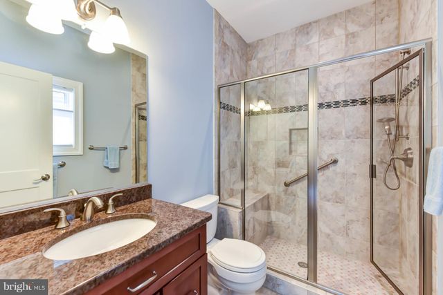 a bathroom with a granite countertop sink toilet mirror and shower
