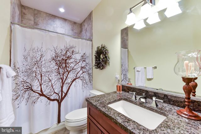 a bathroom with a granite countertop sink a toilet and a mirror