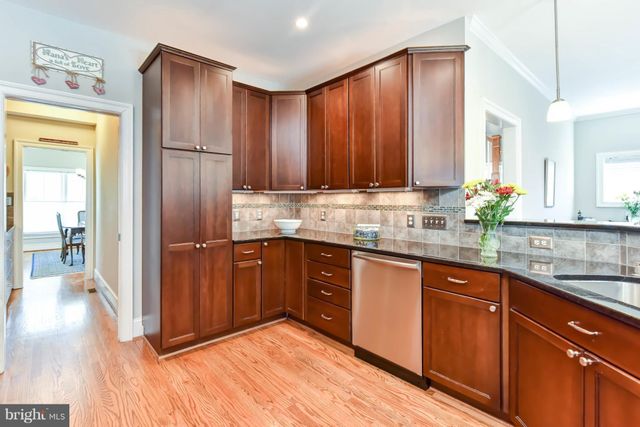 a kitchen with stainless steel appliances granite countertop wooden cabinets a refrigerator and sink