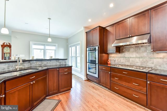 a kitchen with stainless steel appliances granite countertop wooden cabinets a refrigerator and a sink