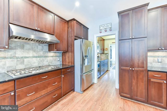 a kitchen with stainless steel appliances granite countertop a refrigerator and wooden cabinets