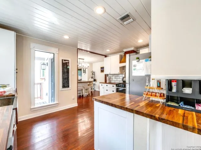 a dining hall with stainless steel appliances granite countertop a refrigerator and wooden floor