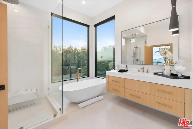 a bathroom with a double vanity sink and mirror with bathtub