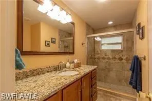 a bathroom with a granite countertop sink a mirror and shower