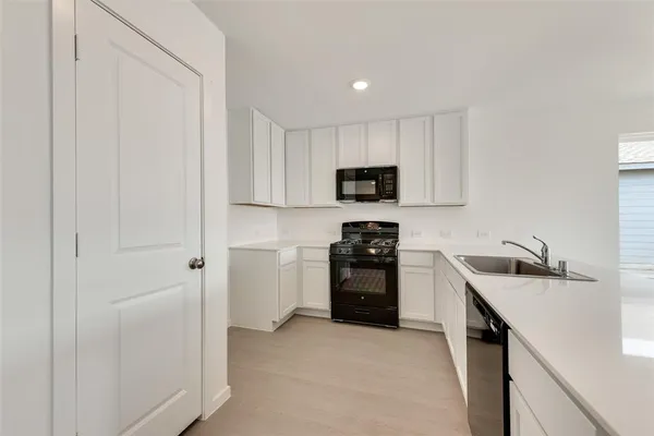 a kitchen with stainless steel appliances a sink a stove a refrigerator cabinets and a window