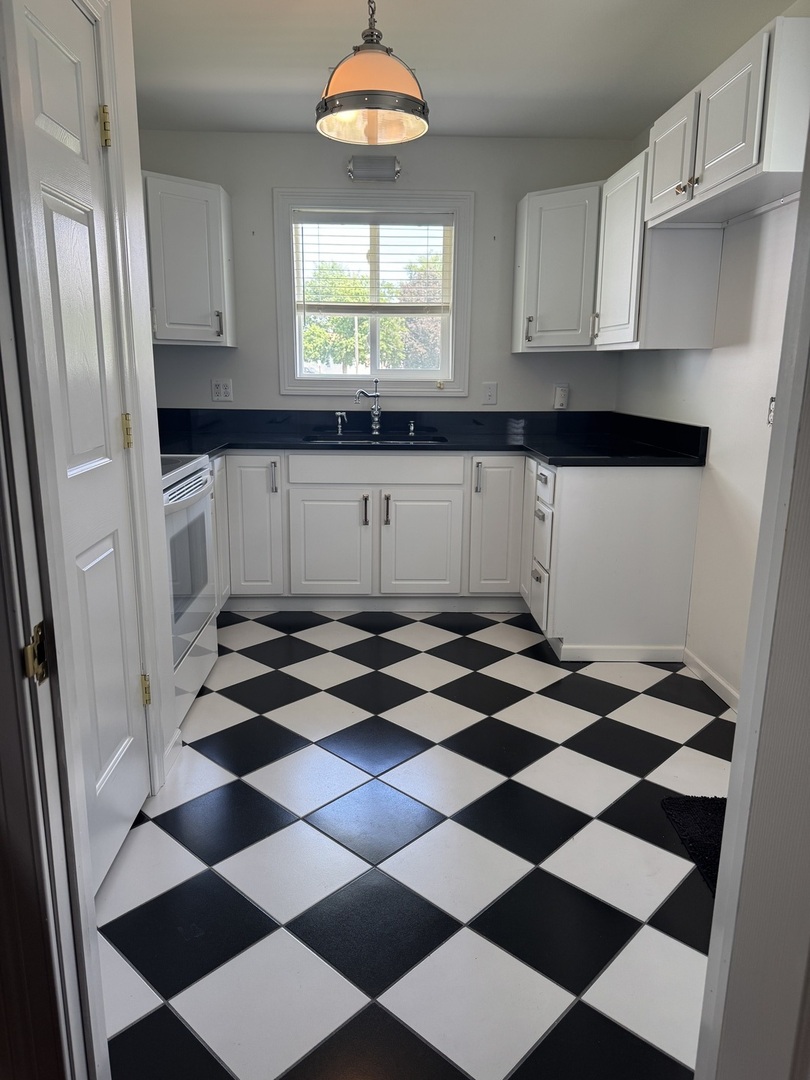 354 19th Place Clinton, IA 52732 - Photo 11 of 16 a kitchen with a checkered floor and white cabinets