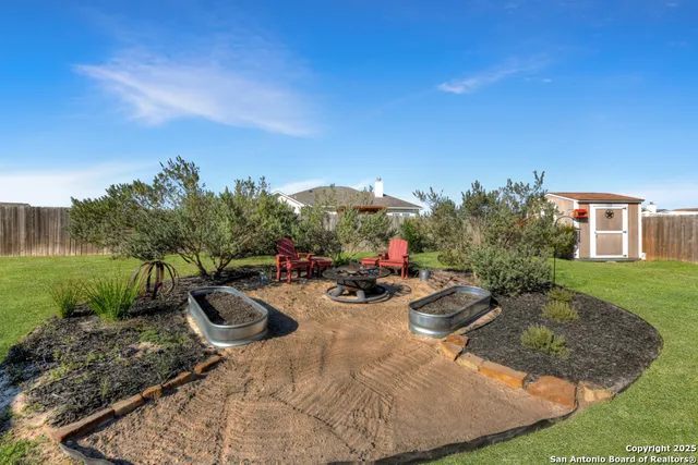 a view of a backyard with couches plants and large tree
