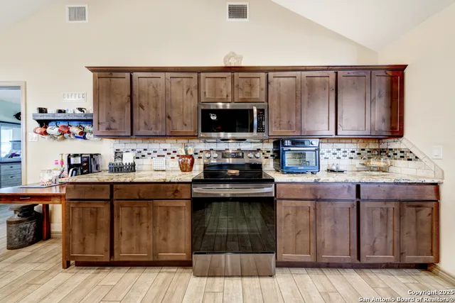 a kitchen with stainless steel appliances granite countertop a stove and a wooden cabinets