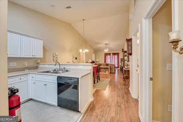 a kitchen with a sink dishwasher a dining table and chairs with wooden floor