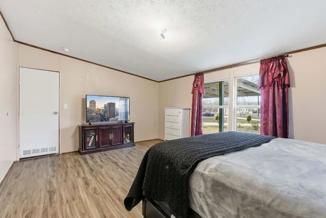 a bedroom with a bed and a dresser next to a window