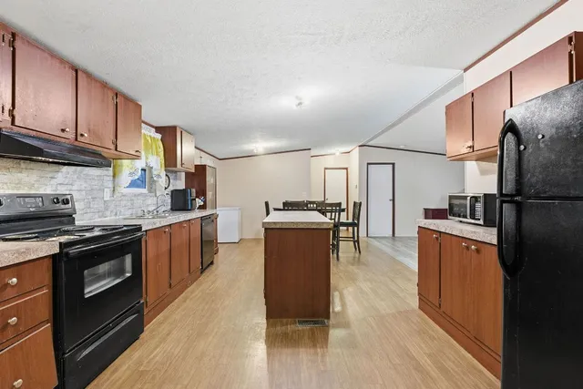 a kitchen with stainless steel appliances granite countertop a refrigerator a stove top oven a sink and dishwasher with wooden floor