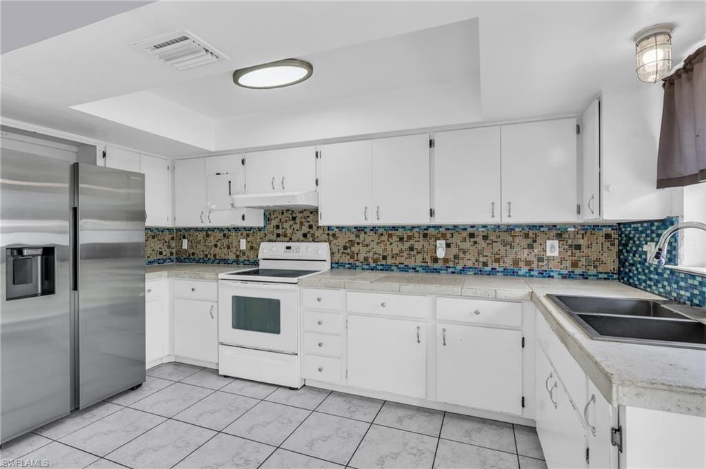2264 53rd Street Southwest Naples, FL 34116 - Photo 14 of 40 Kitchen featuring tasteful backsplash, sink, white range with electric cooktop, and stainless steel refrigerator with ice dispenser