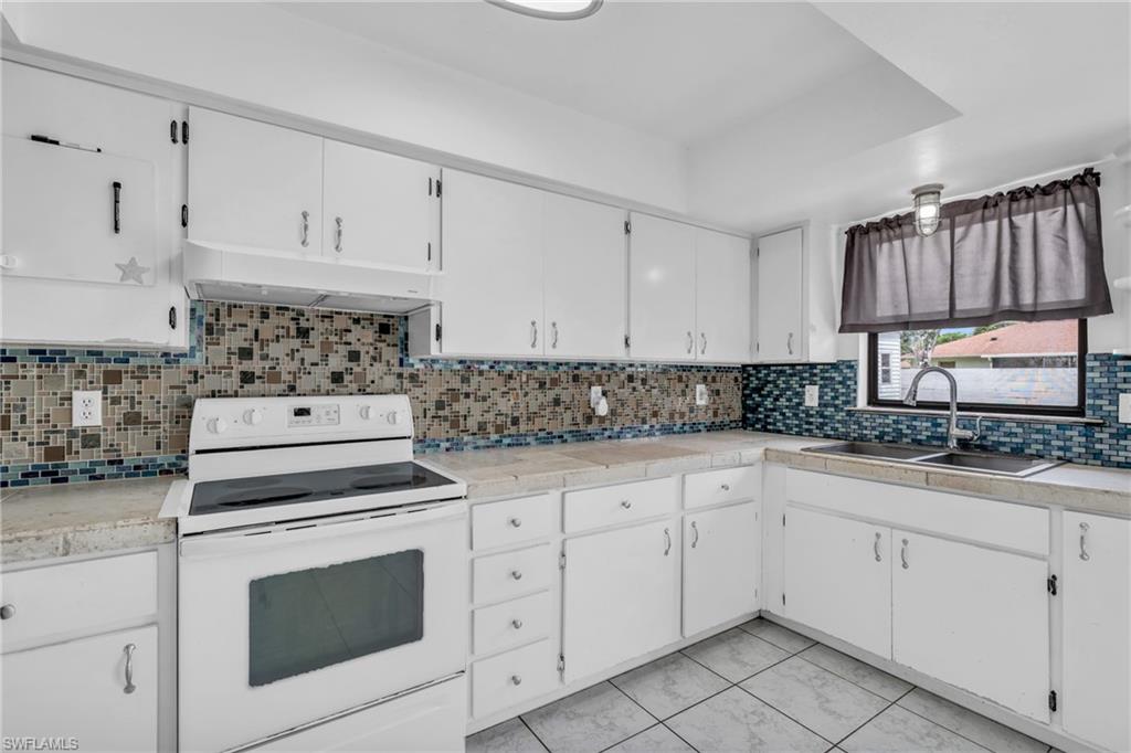 2264 53rd Street Southwest Naples, FL 34116 - Photo 15 of 40 Kitchen featuring white cabinetry, sink, decorative backsplash, and white electric stove