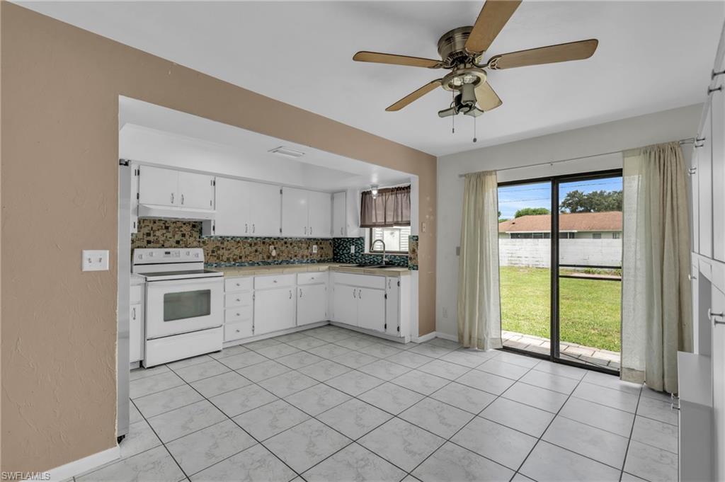 2264 53rd Street Southwest Naples, FL 34116 - Photo 16 of 40 Kitchen featuring white cabinetry, white range with electric stovetop, ceiling fan, and decorative backsplash