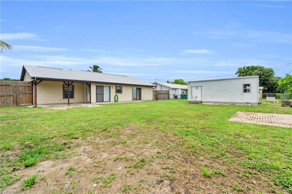 2264 53rd Street Southwest Naples, FL 34116 - Photo 34 of 40 Back of house with an outbuilding, a lawn, and a patio area